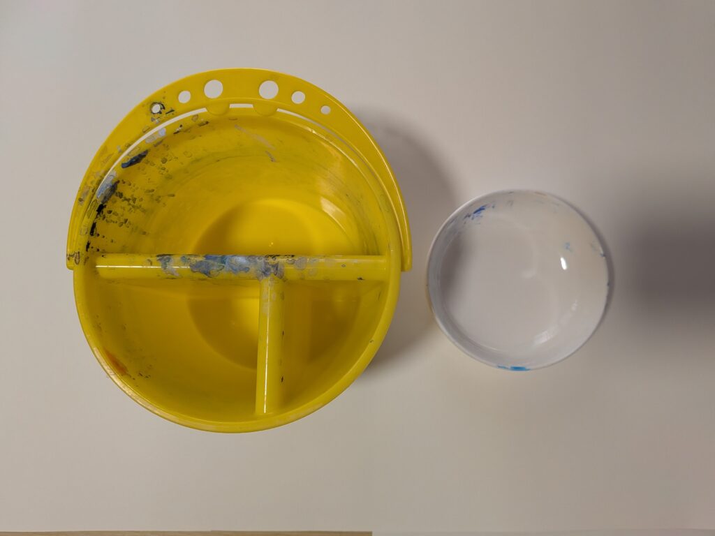 筆洗。上から見ると正円になっており、3口に分かれている。筆洗の横に、白い陶器のやや深さのある小皿が置かれている。